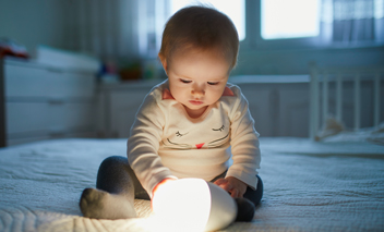 Un bébé joue avec une lampe dans la pépinière.