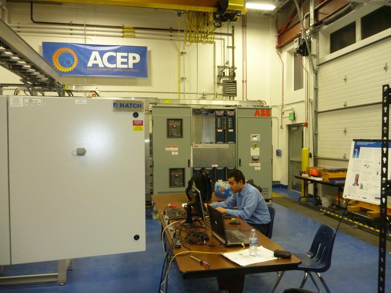 La photographie montre un ingénieur de Hatch travaillant sur un terminal d’ordinateur branché au régulateur de microréseau Hatch dans un laboratoire de l’Alaska