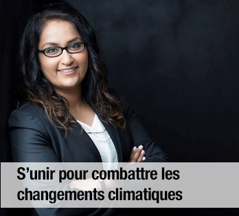 Une femme en tailleur, portant des lunettes, sur un fond sombre -  S’unir pour combattre les changements climatiques 
