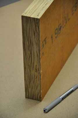 Un panneau en bois de placage stratifié sur chant à côté d’un stylo utilisé comme échelle. 