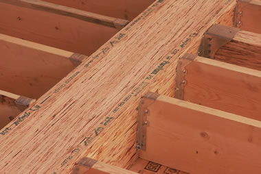 Une poutre en bois de copeaux parallèles à laquelle des pièces de bois sont jointes à l’aide de vis en métal.