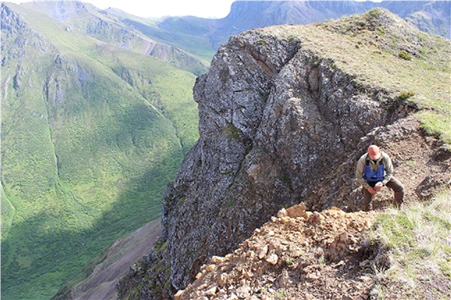 Photo d’un géologue recueillant des échantillons de roche dans une chaîne de montagne.