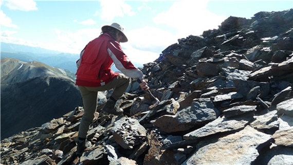 Photo d’un géologue explorant une surface rocheuse pour repérer des zones potentielles de gisement de minerai.