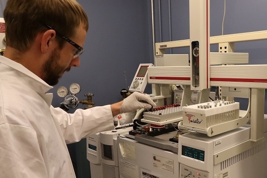Un scientifique place un échantillon sur un chromatographe en phase gazeuse couplé à un spectromètre de masse (CG-SM) afin de faire une analyse.