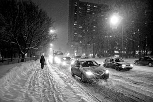 photographie de nuit montrant des véhicules et des piétons dans les rues enneigées de Québec