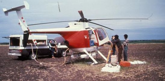 Avion sur le sol avec des techniciens et de l’équipement dans un champ.