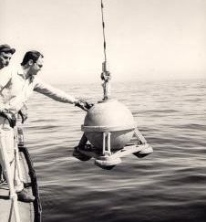 Technicien qui dirige un gravimètre en train d’être descendu dans l'eau.